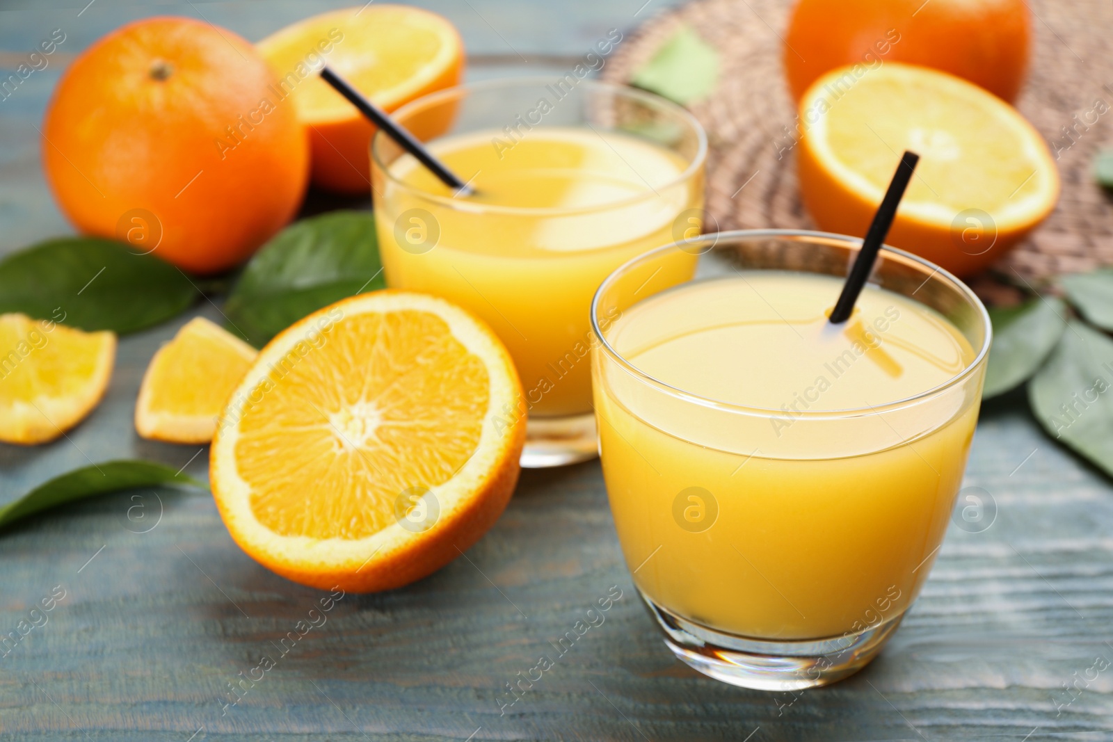 Photo of Delicious orange juice and fresh fruits on light blue wooden table, closeup