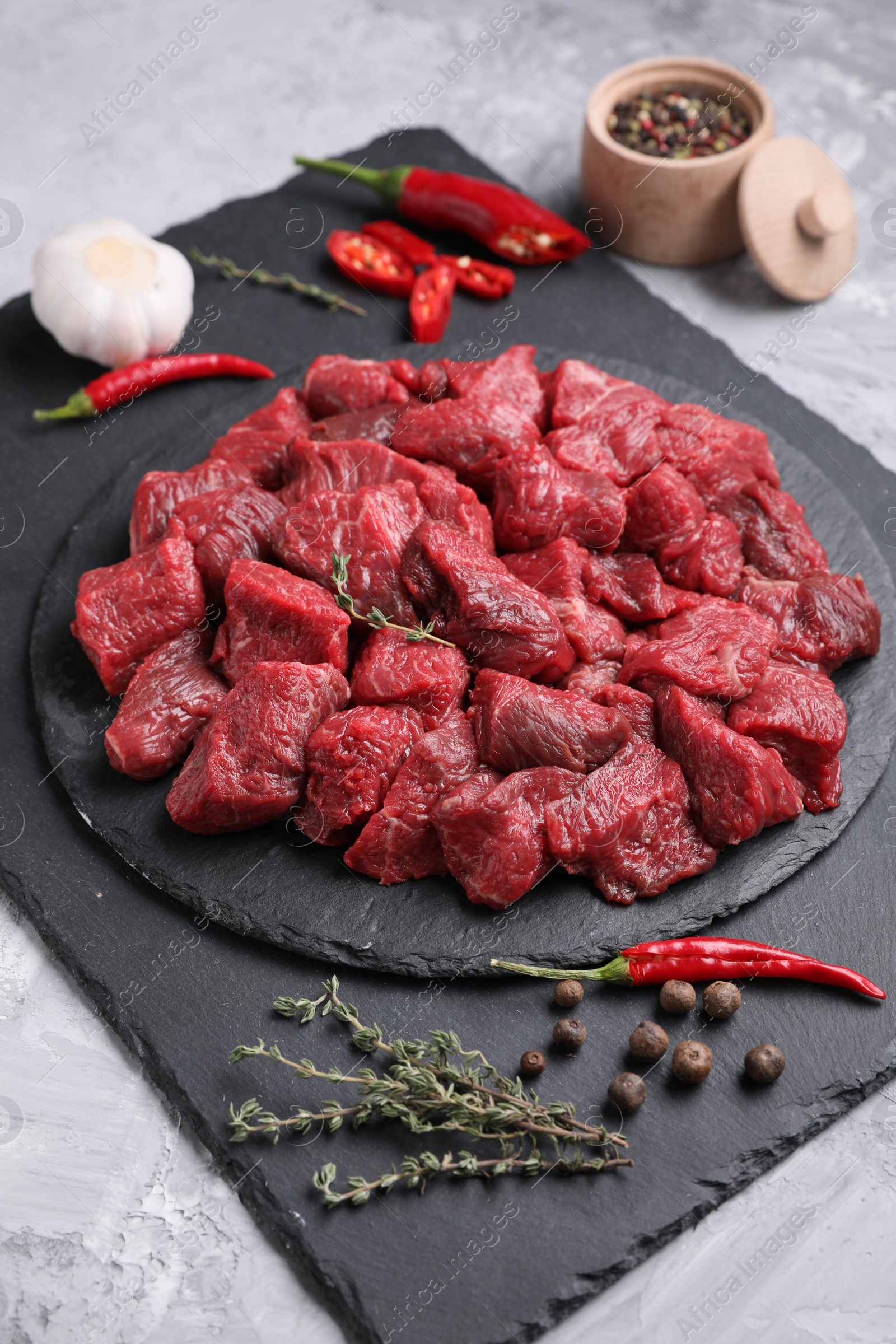 Photo of Pieces of raw beef meat, products and spices on grey textured table