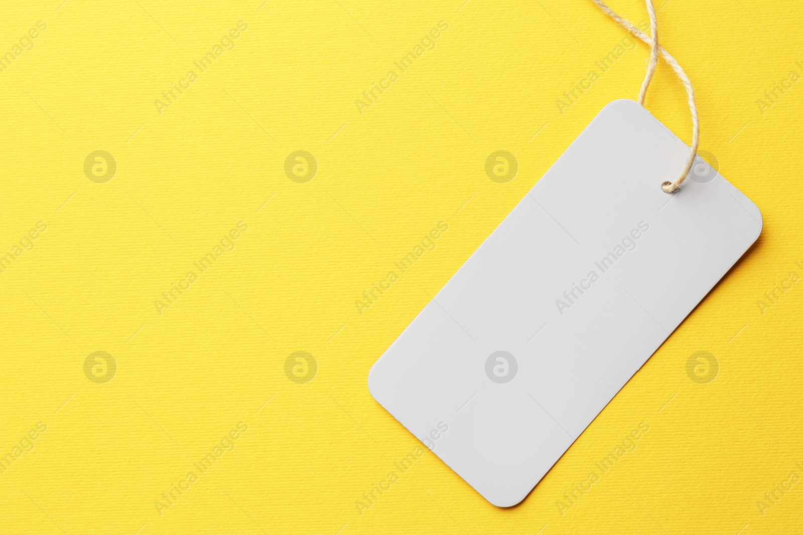 Photo of Tag with space for text on yellow background, top view