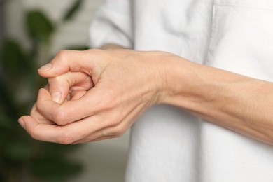 Photo of Woman cracking her knuckles on blurred background, closeup. Bad habit