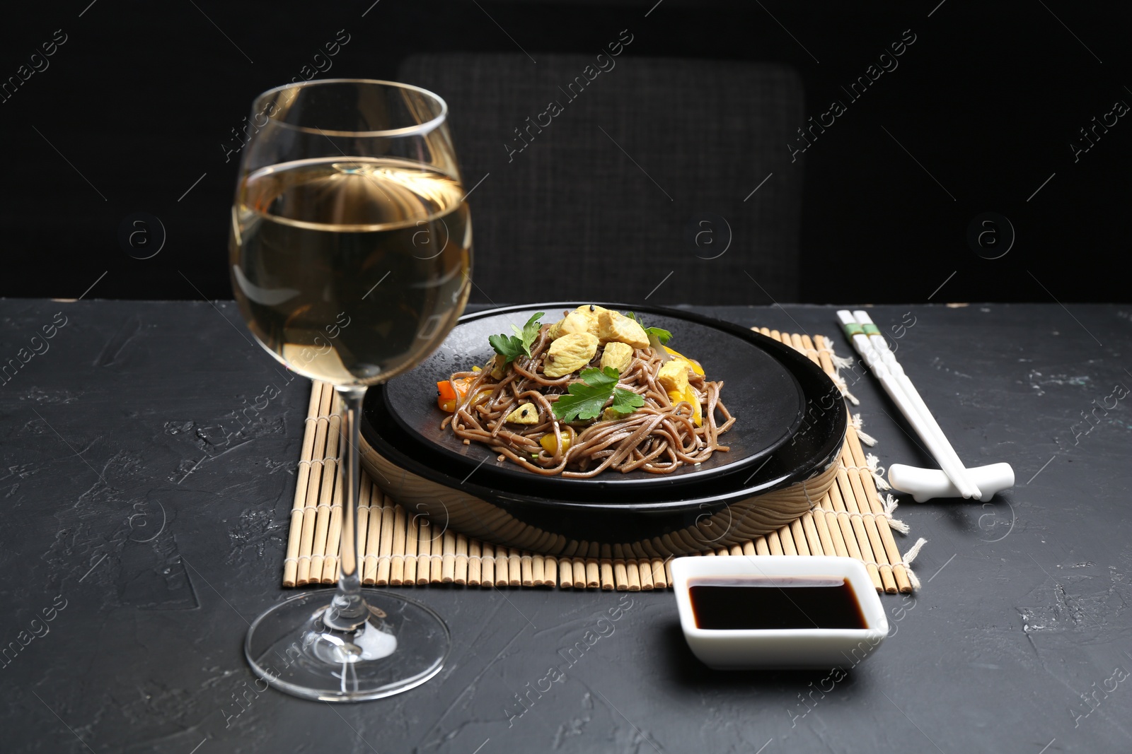 Photo of Stir-fry. Tasty noodles with meat and vegetables served on dark textured table