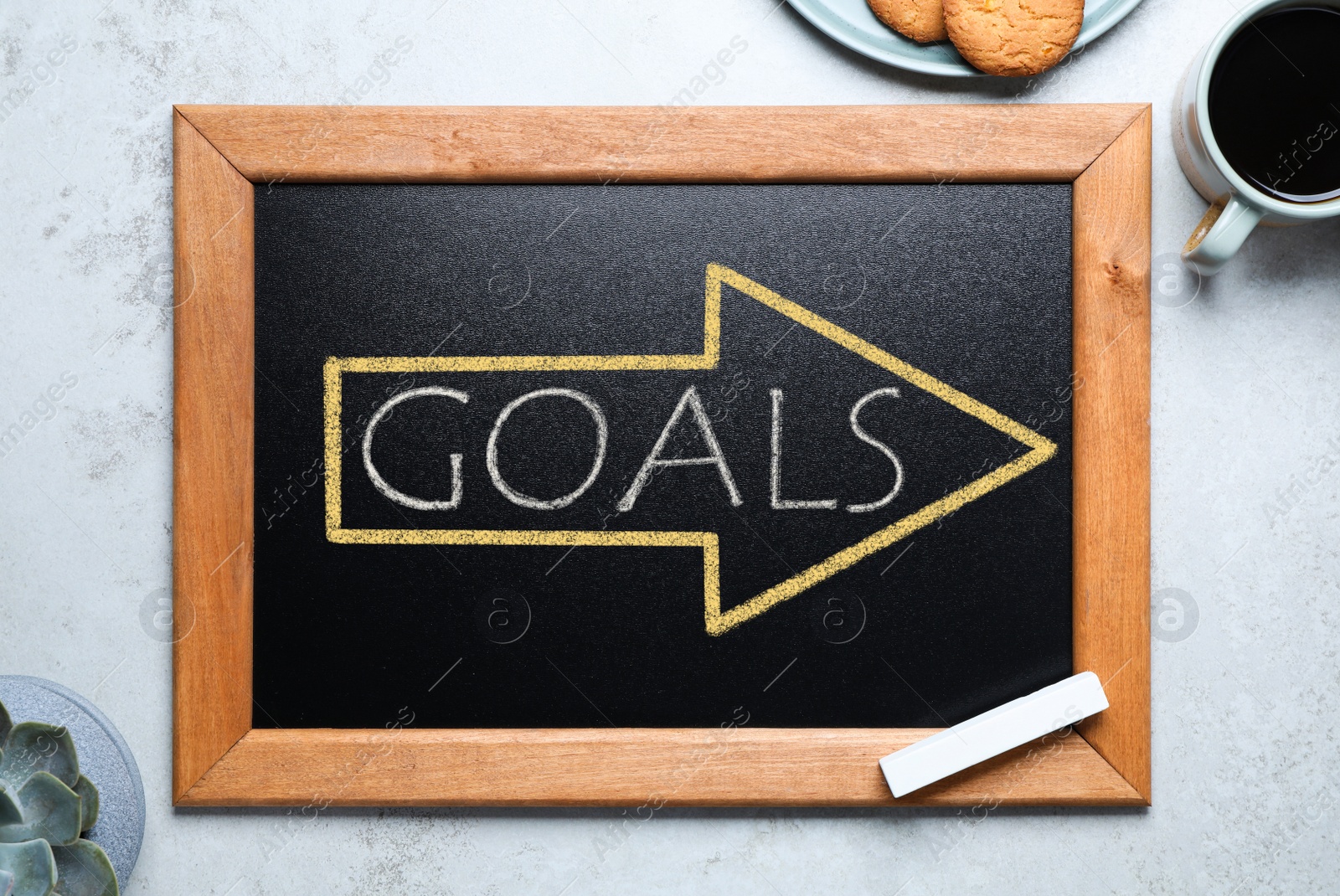 Image of Blackboard with drawn arrow and word GOALS on light grey stone background, flat lay