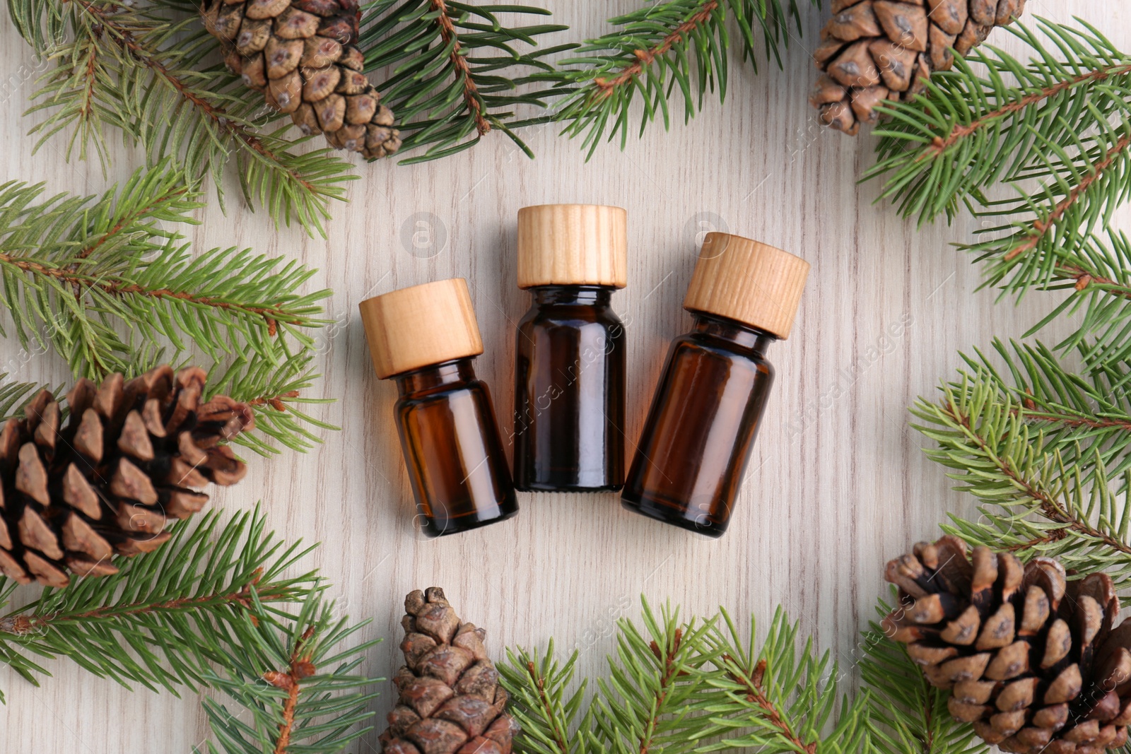 Flat lay composition with pine essential oil, cones and branches on wooden table Photo of Flat lay composition with pine essential oil, cones and branches on wooden table