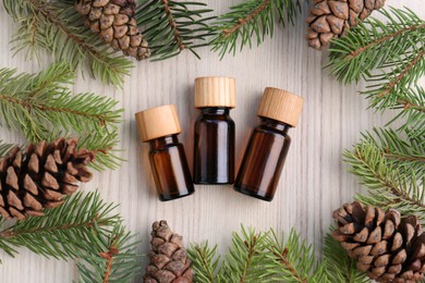 Photo of Flat lay composition with pine essential oil, cones and branches on wooden table