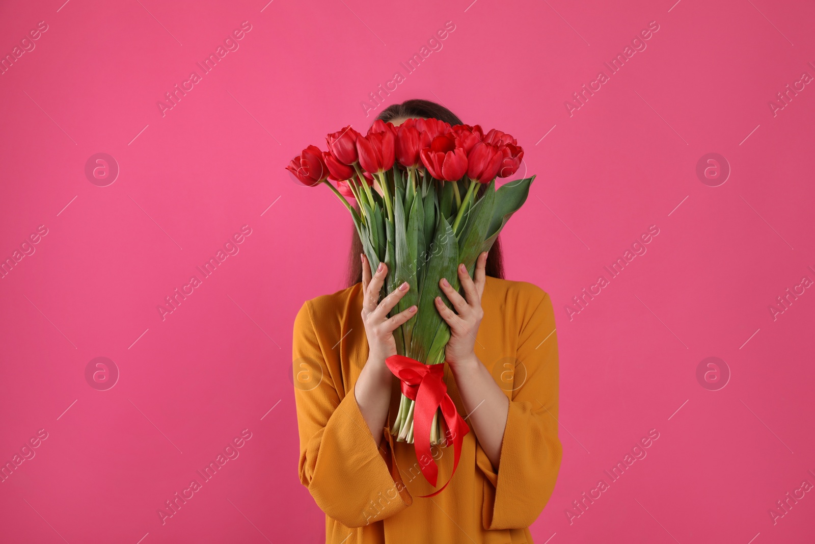 Photo of Woman with red tulip bouquet on pink background. 8th of March celebration