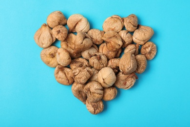 Photo of Heart shaped heap of dried figs on color background, top view. Healthy fruit