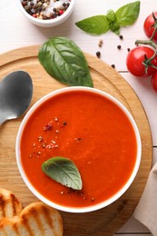 Photo of Delicious tomato soup served on white wooden table, flat lay