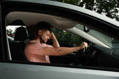 Stressed man in driver's seat of modern car