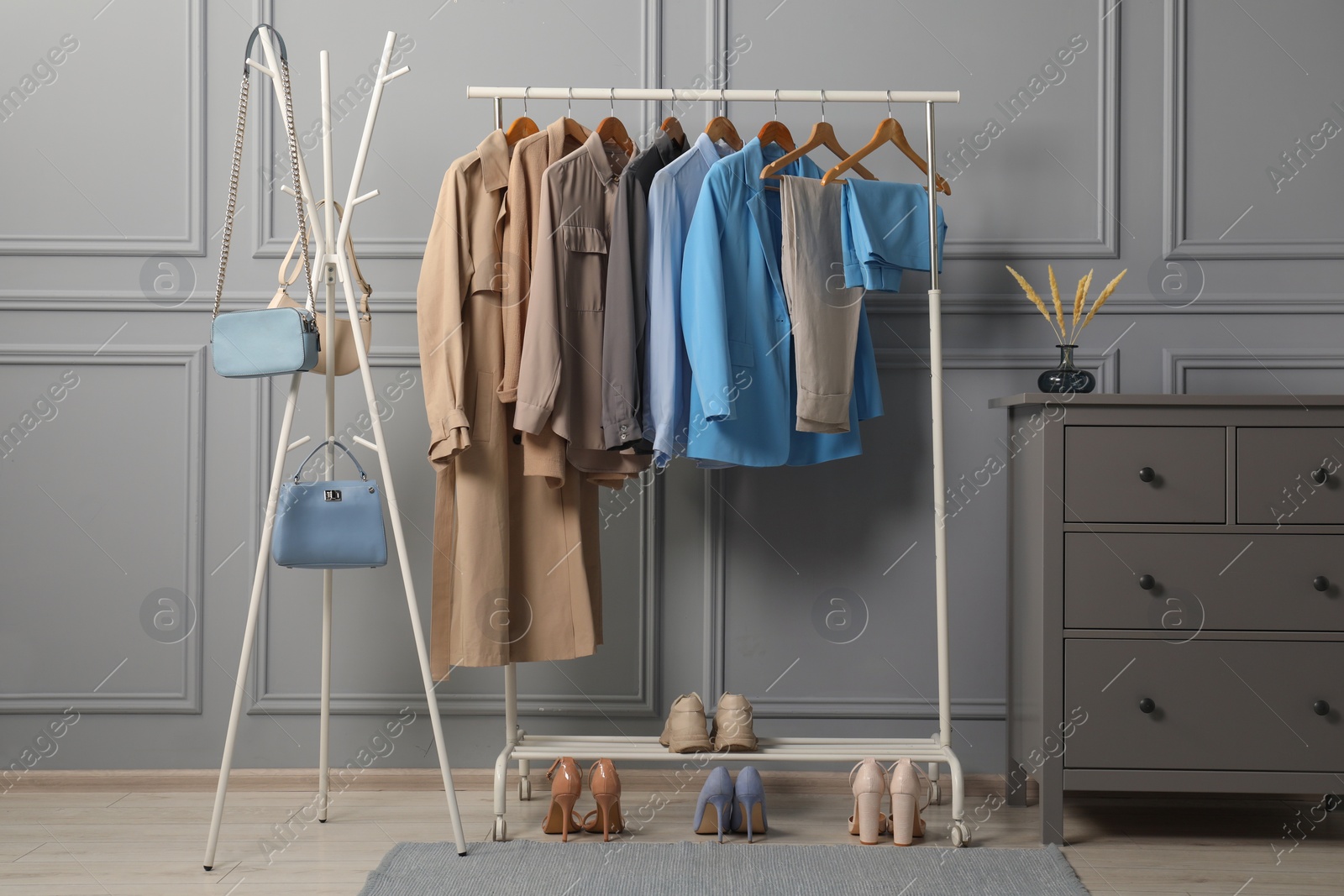 Photo of Rack with different stylish women`s clothes, shoes and bags near grey wall indoors