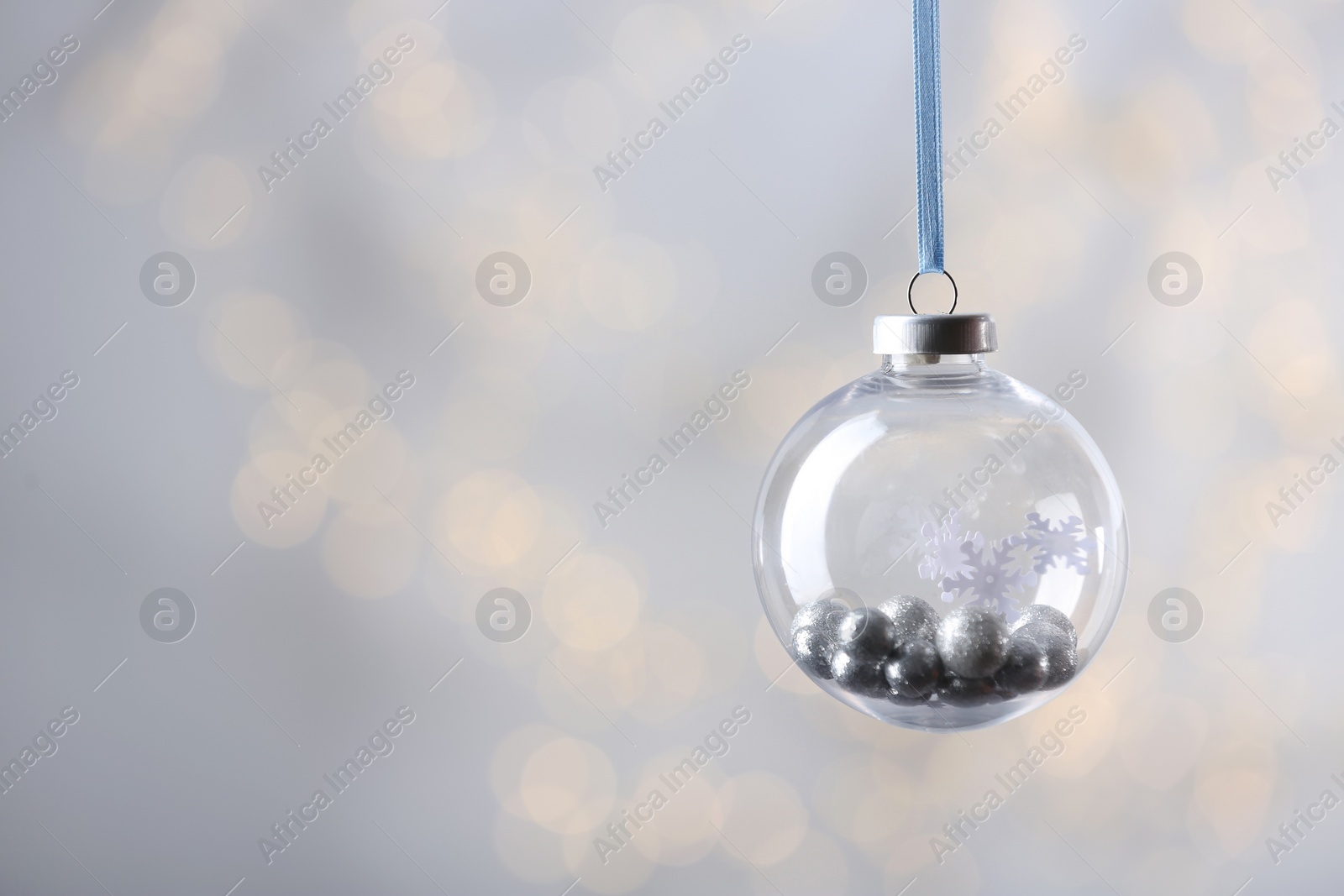 Photo of Decorative snow globe against blurred festive lights, space for text