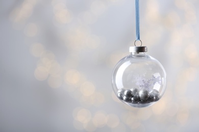 Decorative snow globe against blurred festive lights, space for text