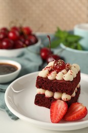 Piece of delicious red velvet cake with fresh berries on white table, closeup