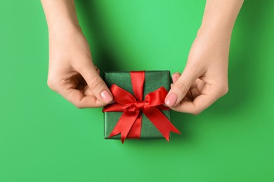 Photo of Woman decorating gift box on green background, top view. Christmas present