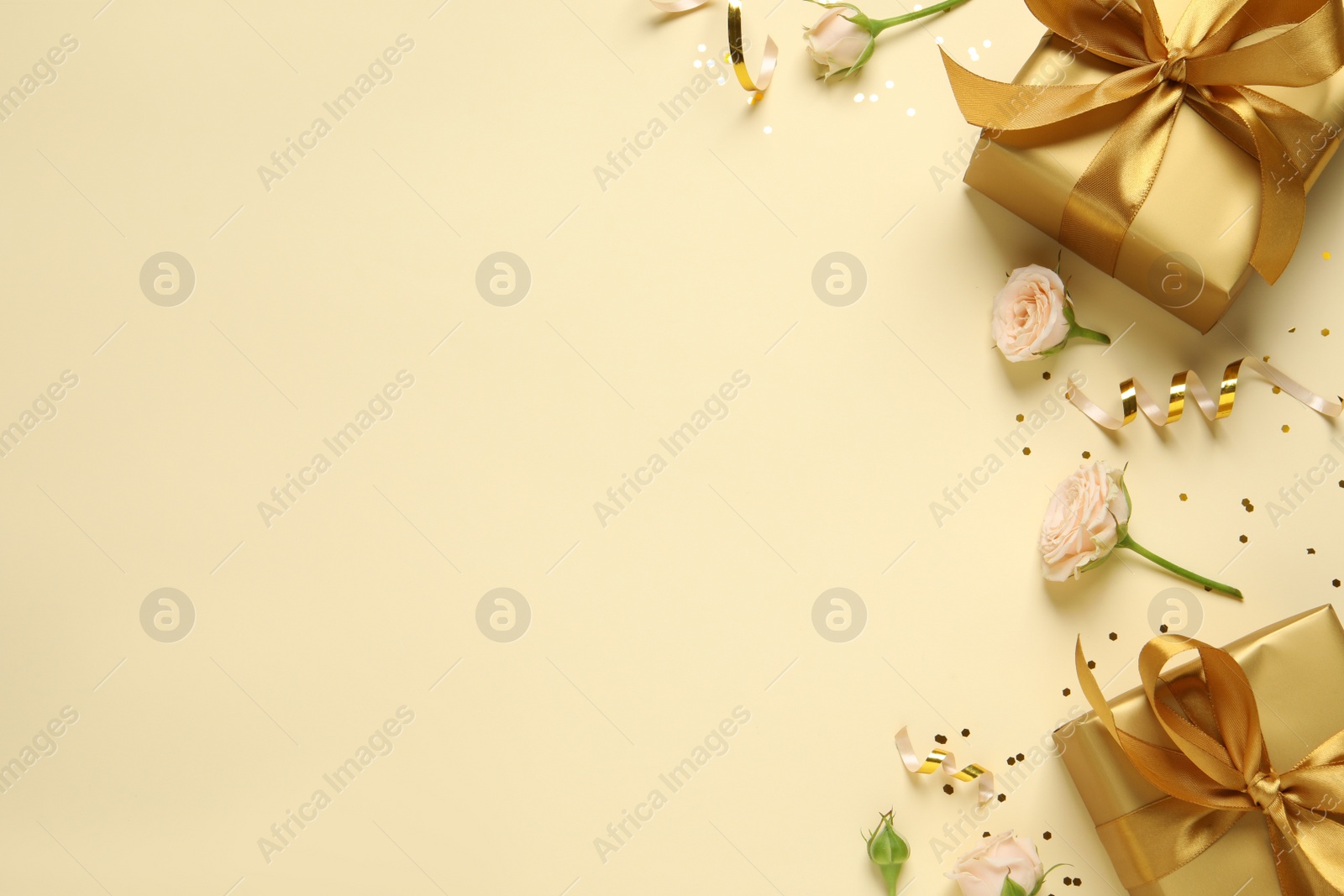 Photo of Beautifully wrapped gift boxes, flowers and confetti on beige background, flat lay. Space for text