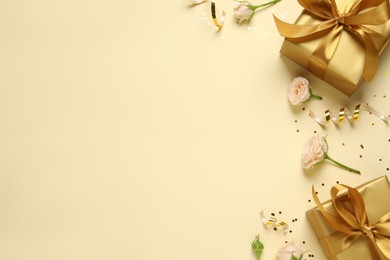 Beautifully wrapped gift boxes, flowers and confetti on beige background, flat lay. Space for text