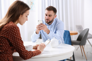 Couple addicted to smartphones ignoring each other in cafe. Relationship problems