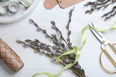 Photo of Beautiful bouquet of pussy willow branches and wrapping materials on white wooden table, flat lay