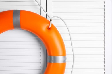 Photo of Orange lifebuoy on white wooden background, space for text. Rescue equipment