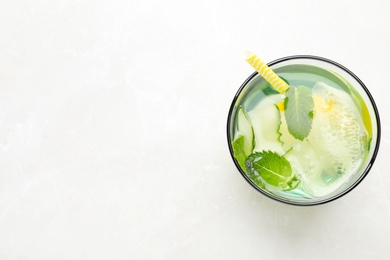 Refreshing water with cucumber, lemon and mint on white table, top view. Space for text