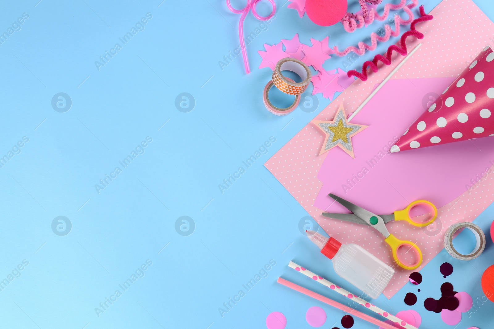 Photo of Flat lay composition with different materials to create party hats on light blue background, space for text. Handmade decoration