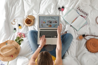 Woman and laptop with open cooking blog on bed, top view