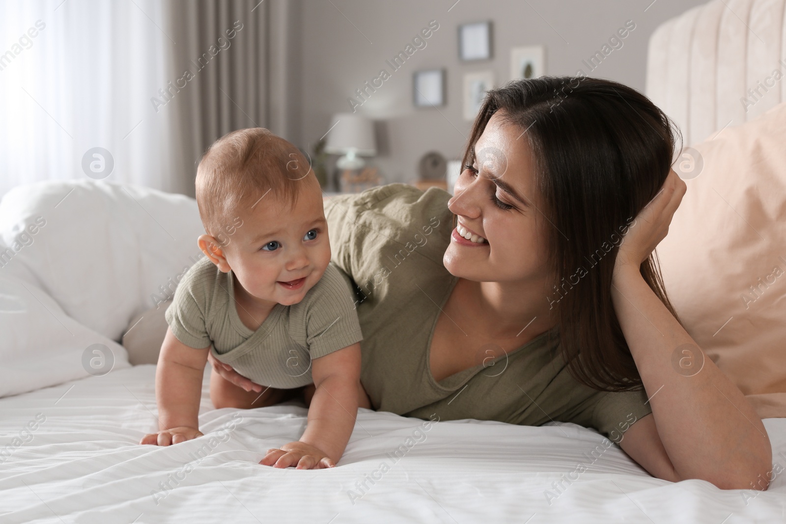 Photo of Happy young mother with her cute baby on bed at home