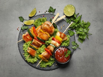 Photo of Delicious chicken shish kebabs with vegetables on grey table, flat lay
