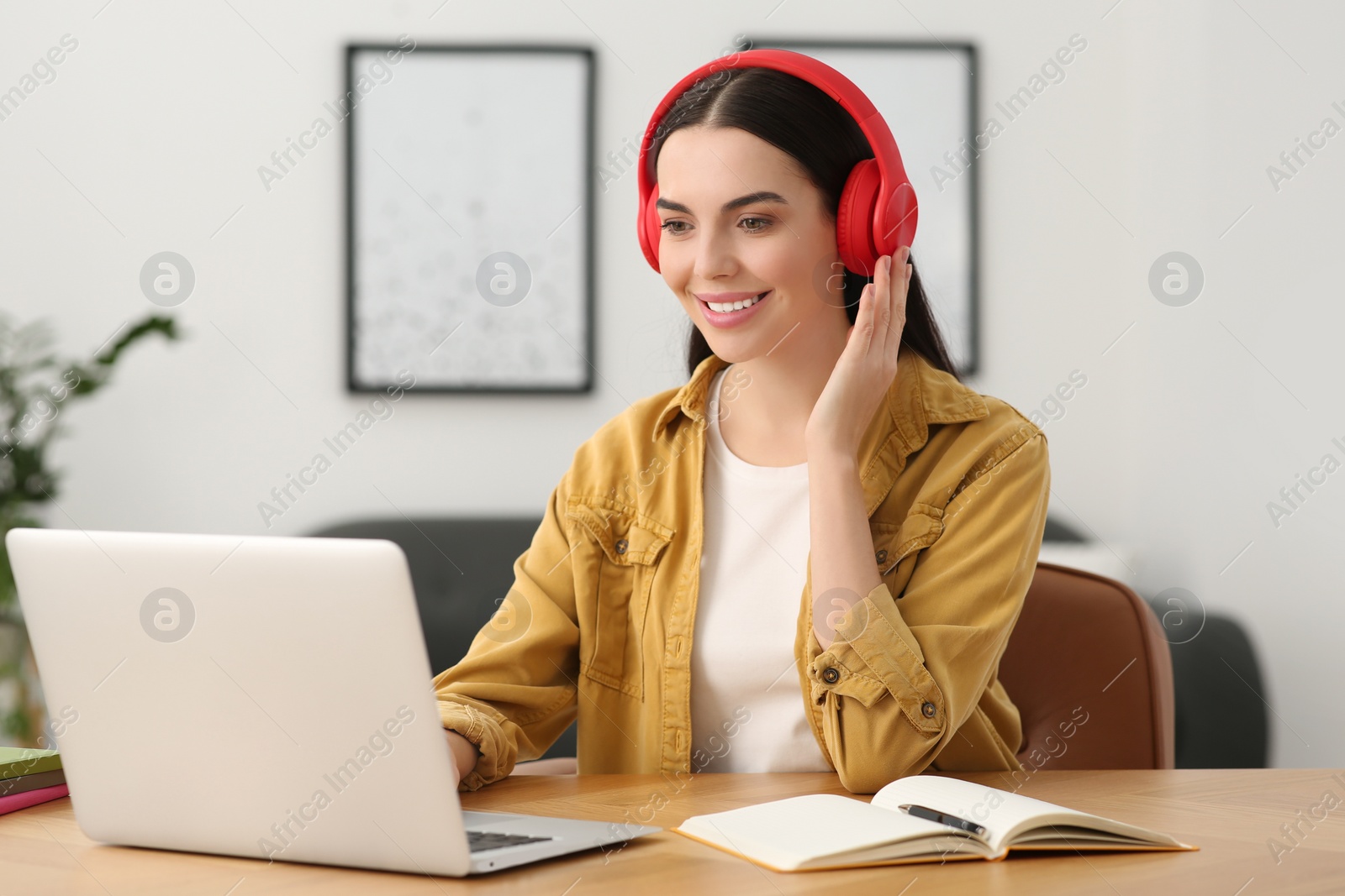 Photo of Woman in headphones studying on laptop at home. Online translation course