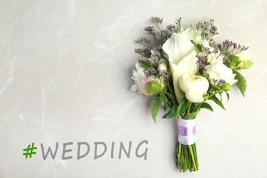 Bouquet of beautiful flowers and hashtag Wedding on light grey marble table, top view