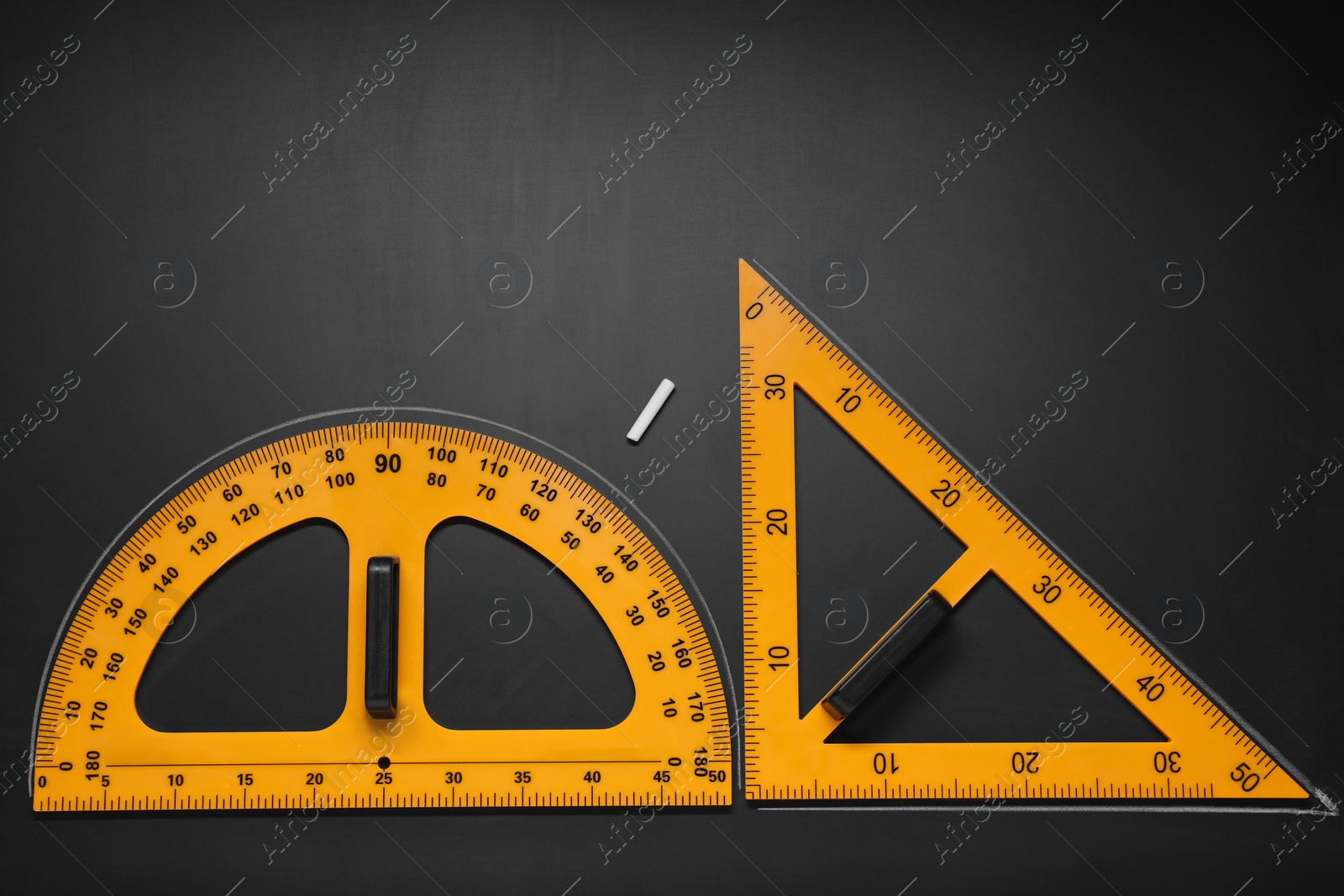 Photo of Protractor, triangle ruler and chalk on black table, flat lay. Space for text