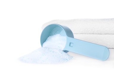 Laundry detergent in plastic measuring scoop and towels on white background