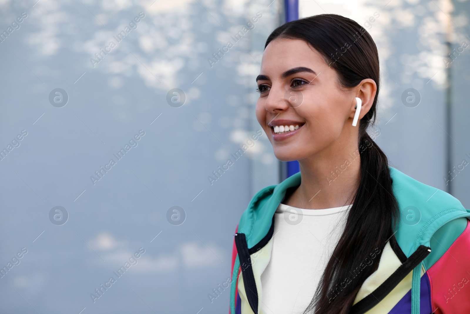 Photo of Young sportswoman with wireless earphones on city street