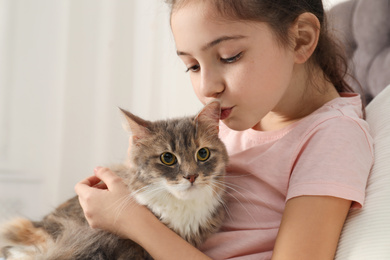 Cute little girl with cat at home, closeup. First pet