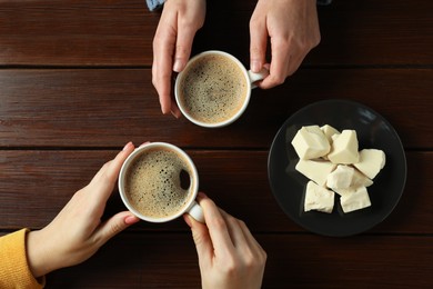 Photo of Women having coffee break at wooden table, top view