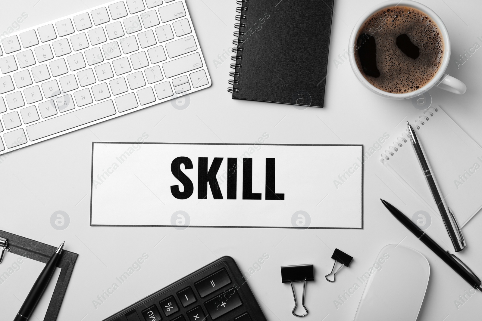 Photo of Word SKILL, keyboard, cup of coffee and stationery on white background. Business trainer concept