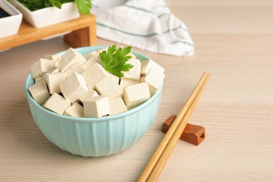 Delicious tofu with parsley and chopsticks on wooden table, closeup
