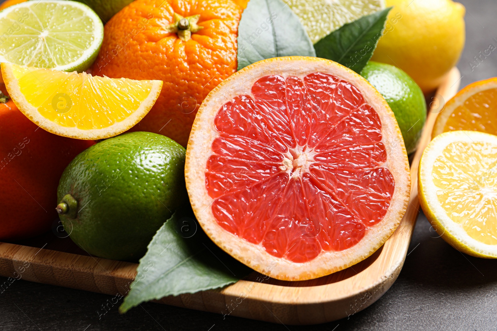 Photo of Different citrus fruits on black table, closeup