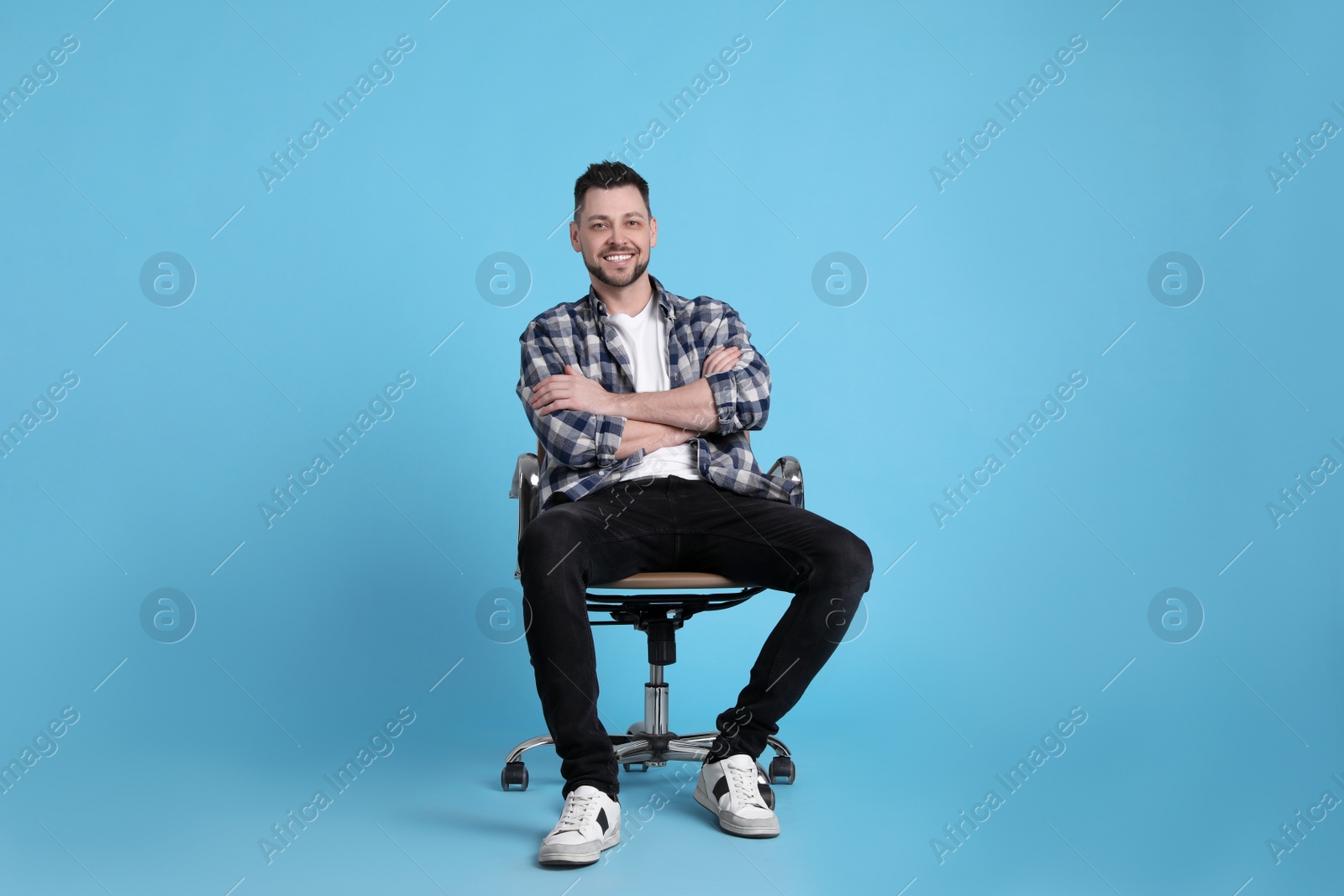 Photo of Handsome man sitting in office chair on light blue background