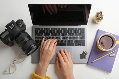 Female photographer using laptop at table, top view