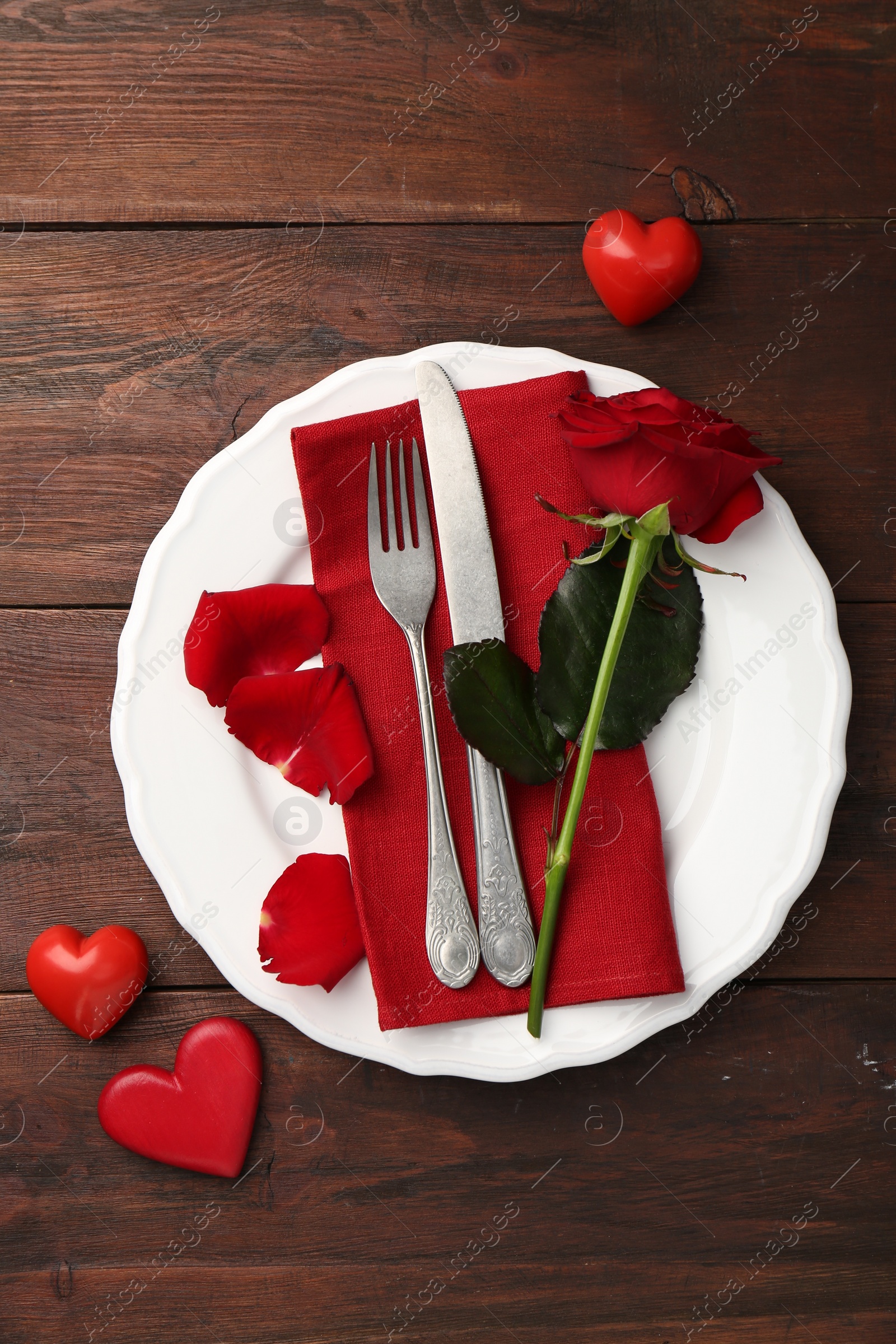 Photo of Romantic place setting with red rose and decorative hearts on wooden table, top view. St. Valentine's day dinner