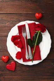 Romantic place setting with red rose and decorative hearts on wooden table, top view. St. Valentine's day dinner