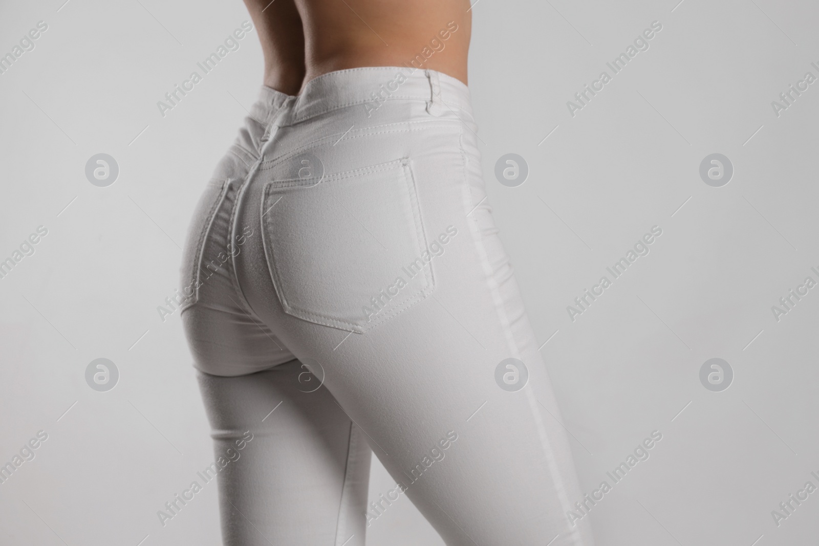 Photo of Woman in stylish white jeans on light background, closeup