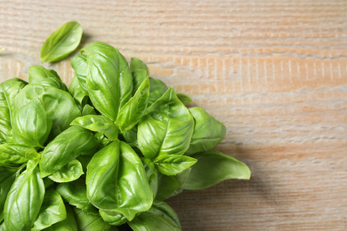 Photo of Fresh basil on wooden table, top view. Space for text