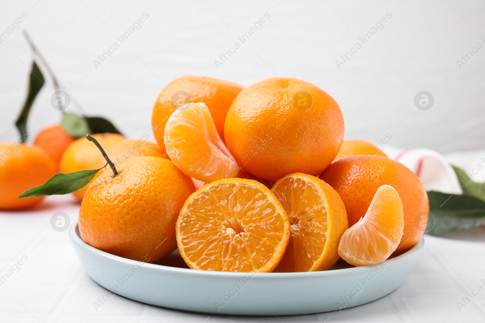 Photo of Fresh juicy tangerines on white tiled table