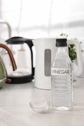 Photo of Cleaning electric kettle. Bottle of vinegar and baking soda on countertop in kitchen