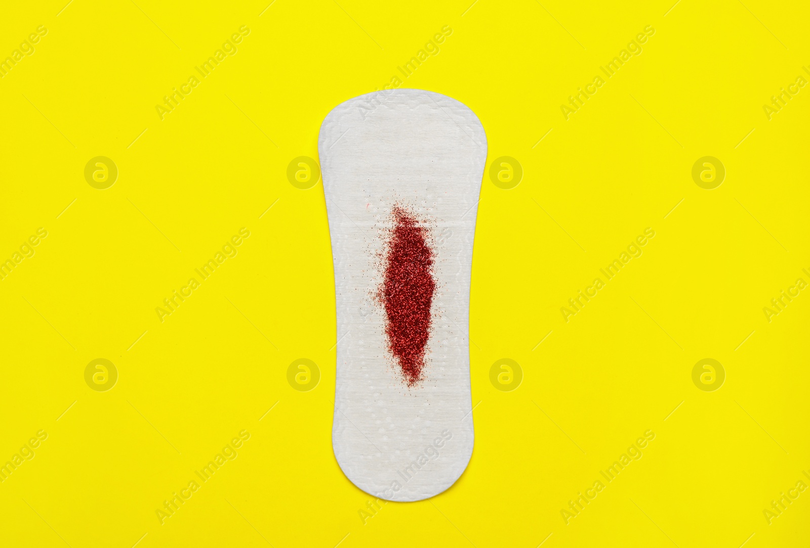 Photo of Sanitary pad with red glitter on yellow background, top view. Menstrual cycle