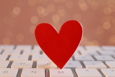 Photo of Red decorative heart on laptop keyboard, closeup. Online dating concept