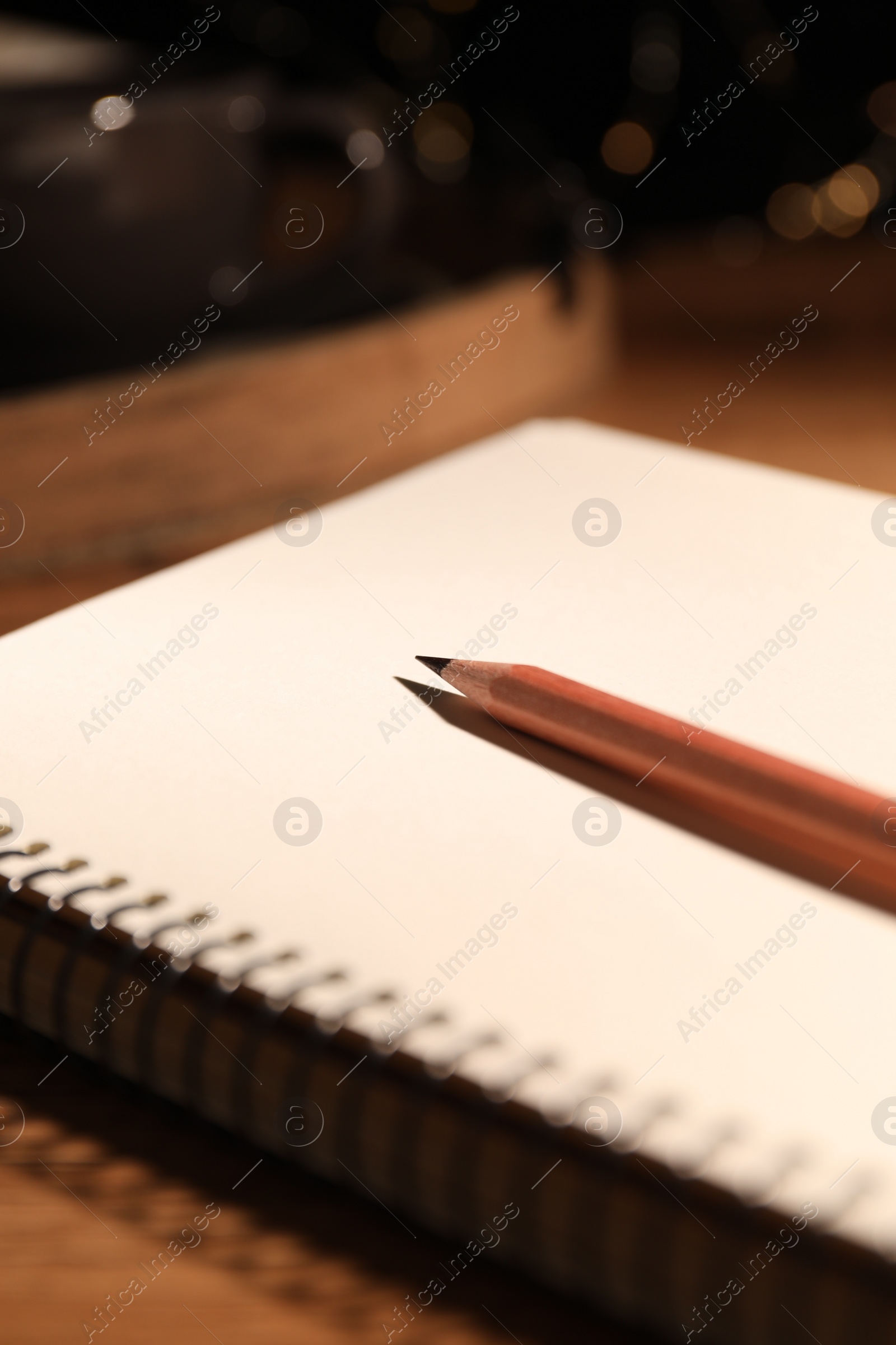 Photo of Blank notebook and pencil on wooden table, closeup