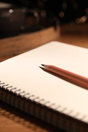 Photo of Blank notebook and pencil on wooden table, closeup