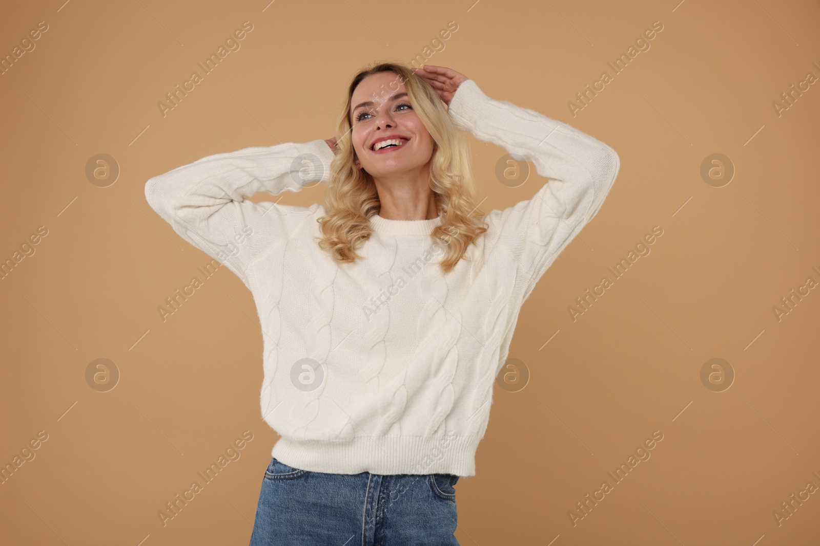 Photo of Happy woman in stylish warm sweater on beige background